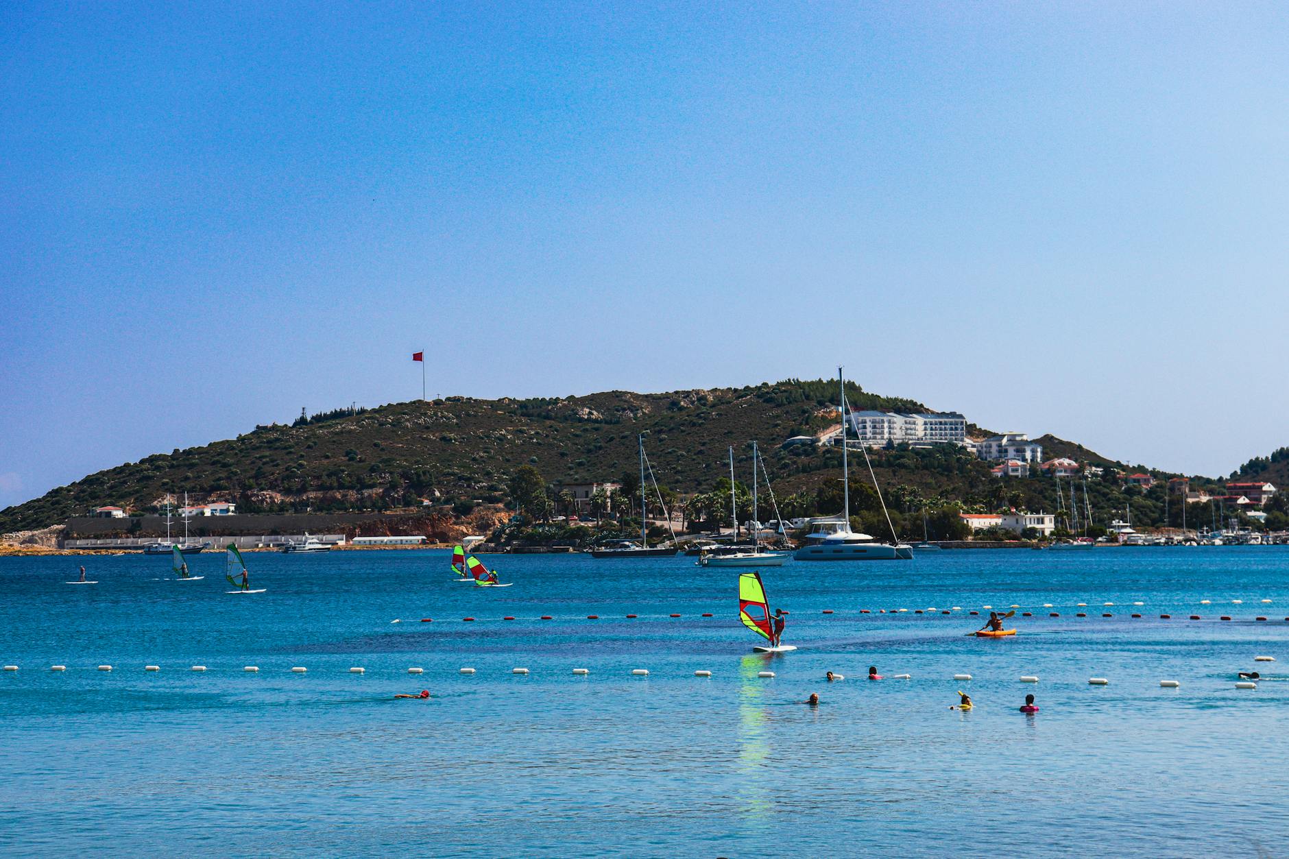 Idyllic bay with windsurfing and swimming amidst hillside views and yachts.