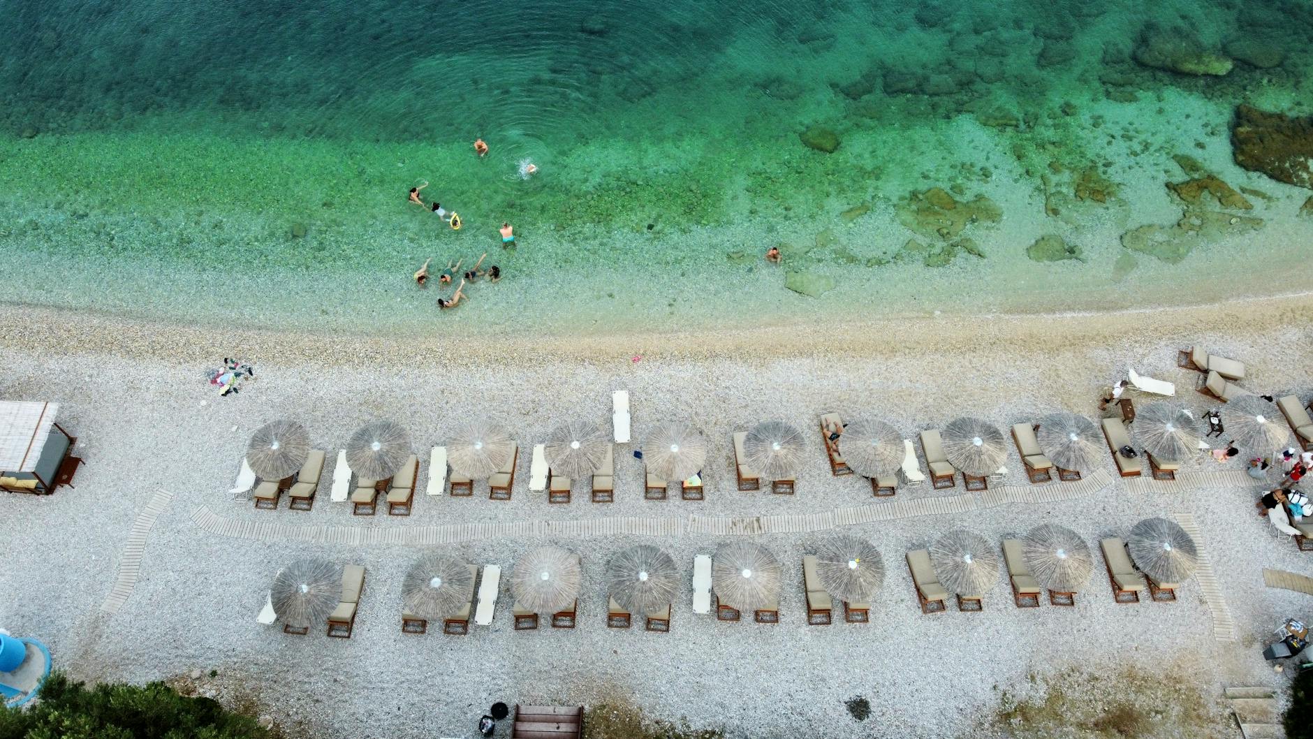 Relaxing aerial view of Alonnisos beach, Greece with turquoise sea and sunbathers.